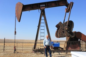 Doug Cooper stands infront of an oil well 